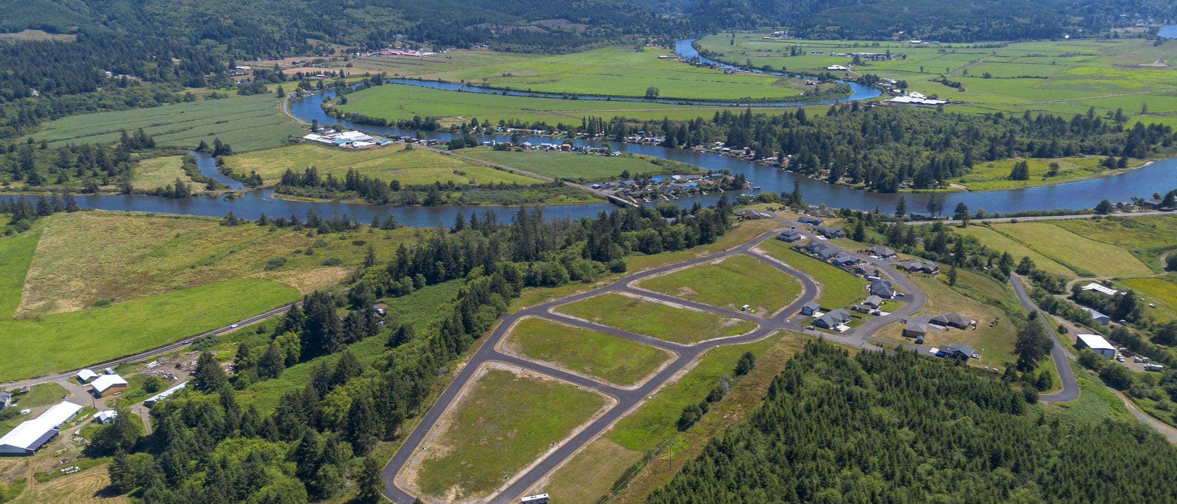 Aerial of the Riverview Meadows lots and paved roads, with the Nehalem River and farmland behind